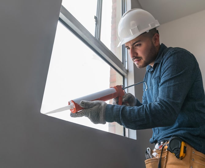 Repair man caulking a window